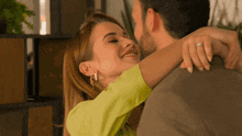 a man and woman are hugging and the woman is wearing a yellow shirt