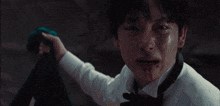 a man in a white shirt and black tie is crying with blood on his face