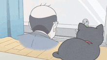 a bald man is looking out a window while a cat watches