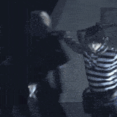 a man in a black and white striped shirt stands next to another man in a black and white striped shirt
