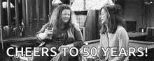 two women are sitting next to each other in front of a pool table in a bar .