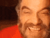 a close up of a man 's face with a beard smiling .