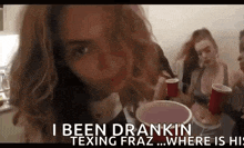 a woman is drinking from a red cup while a group of women are sitting around her .