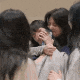 a group of women are hugging each other in a room and one of them is crying .