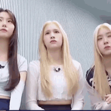 three women are standing next to each other and looking at the camera .
