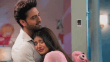 a man and a woman are hugging each other in a room . the woman is crying and the man is smiling .