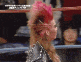 a woman with a mohawk stands in a wrestling ring with chinese writing on the screen