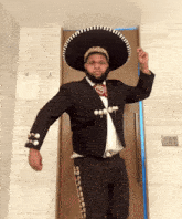 a man wearing a sombrero and a supreme bandana stands in front of a door