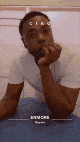 a man in a white shirt is sitting down with his hand on his chin and the words enmore guyana on the bottom
