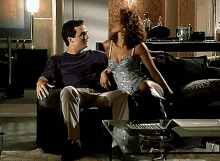 a man in a purple shirt sits next to a woman in a silver dress on a couch