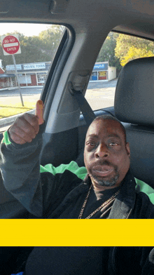 a man in a car giving a thumbs up in front of a natural foods store