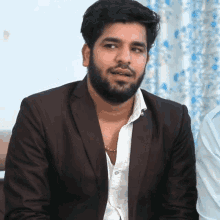 a man with a beard is wearing a brown jacket