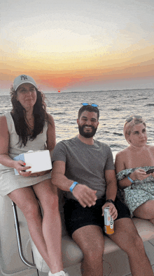 a man wearing a ny hat sits on a boat with two other people