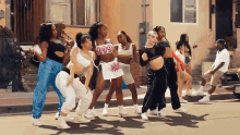 a group of women are dancing on the side of the road .
