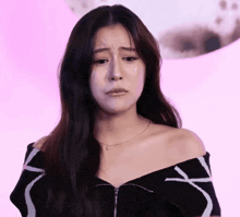 a woman with a tear running down her cheek is wearing a black off the shoulder top