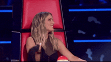 a woman sitting in a red chair with a red button on the table