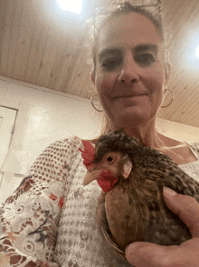 a woman is holding a small chicken with a red crest