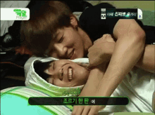 two young men are laying on a bed and one of them is holding the other 's arm