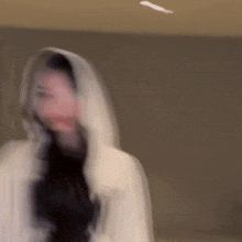 a blurry picture of a woman wearing a white hooded coat