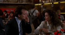 a man and a woman are sitting at a table with the words what a waste written below them