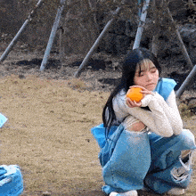 a woman is kneeling down holding an orange in her hands