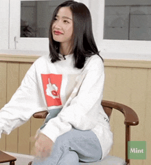 a woman is sitting in a chair with a mint sticker on the bottom
