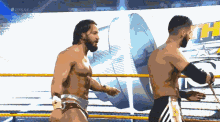 two wrestlers are standing in a ring with a sign that says # 20live