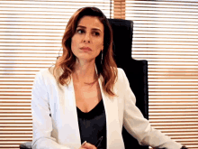a woman in a white jacket is sitting in an office chair