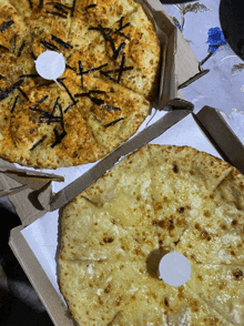 two pizzas are sitting on a table and one has a white sticker on it