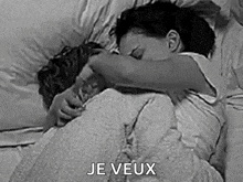 a man and a woman are hugging each other in bed .
