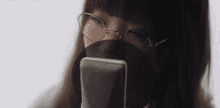 a woman wearing glasses is using a cell phone .