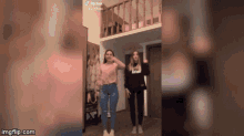 a couple of girls are dancing in a room with a staircase behind them .