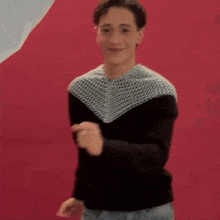 a man in a black and white sweater is dancing on a red background