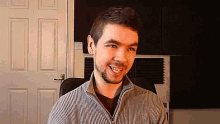 a man with a beard is smiling while sitting in a chair