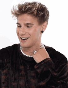 a young man wearing a pearl necklace and black earrings