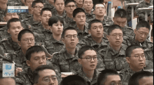 a large group of soldiers are sitting in a classroom watching a lecture