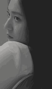 a black and white photo of a woman in a white shirt looking over her shoulder .