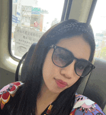 a woman wearing sunglasses sits in front of a window with a sign that says 03-531b on it