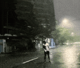 a man in a white shirt is standing in the rain on a city street