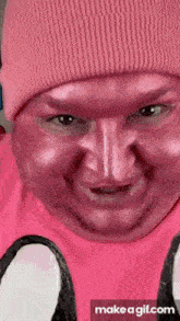 a man wearing a pink beanie and a pink shirt has a pink face painted on his face .