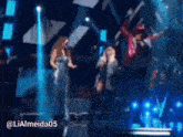 a man in a red jacket is jumping in the air on a stage with a woman singing