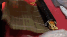 a person is rolling a sushi roll on a cutting board with a knife .