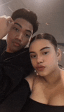 a man and a woman are posing for a picture together . the woman is wearing a black top .