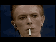 david bowie is smoking a cigarette in a close up of his face .
