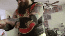 a man with a beard and tattoos is wearing a red and gold vest