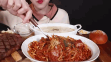 a woman is cutting a piece of spaghetti with a knife .
