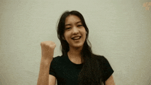 a woman in a black shirt is smiling and holding her fist up