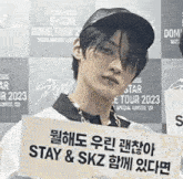 a young man holds a sign that says stay & skz