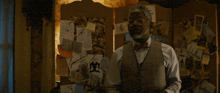 a man in a vest and bow tie is standing in front of a wall that says right fucking now