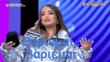 a woman in a silver jacket is holding a black purse and says " baptisia "